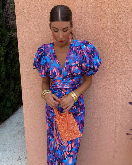 Close-up of a women's cocktail dress featuring a blue and purple floral print, V-neck, and elegant puff sleeves with ruched detailing.