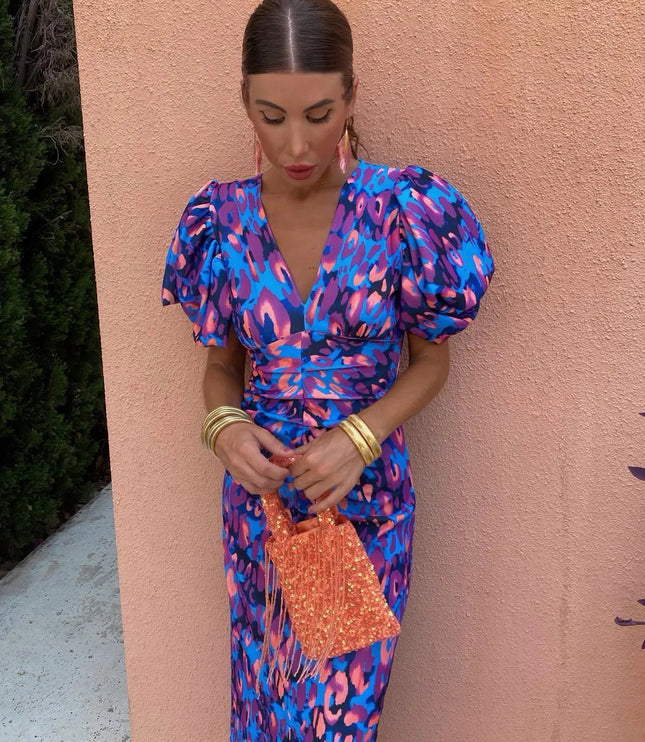 Close-up of a women's cocktail dress featuring a blue and purple floral print, V-neck, and elegant puff sleeves with ruched detailing.