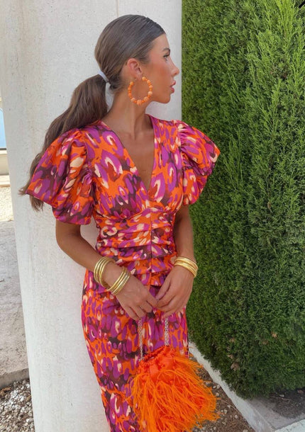 Women's cocktail dress in a vibrant orange and purple floral pattern with puff sleeves and a V-neck, cinched waist, and midi length.