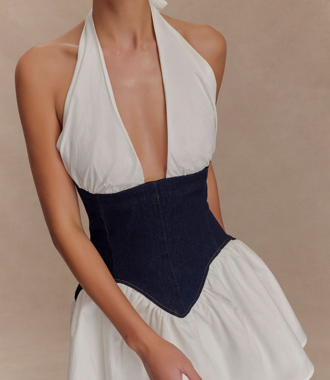 Close-up of halter neckline and dark denim corset bodice on women’s cocktail mini dress