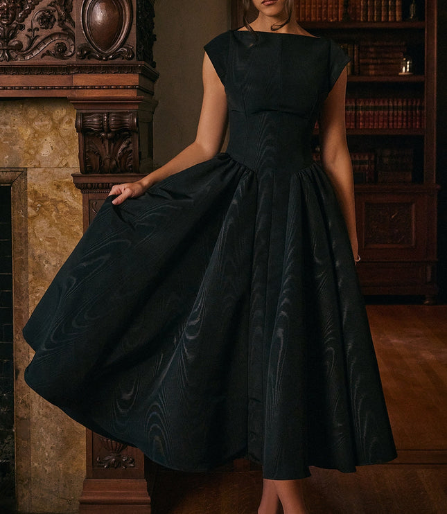 Model wearing black open back midi cocktail dress in a library setting