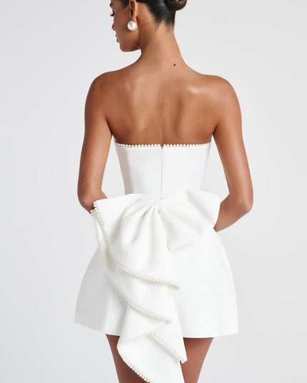 Back view of white strapless dress with pearl trim and dramatic bow detail