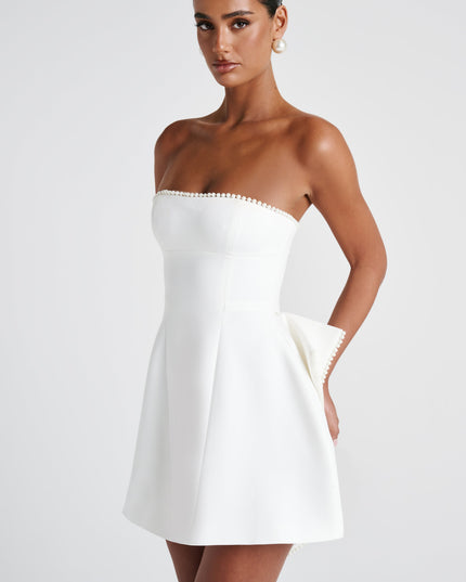 White strapless mini dress with pearl trim and asymmetrical bow on skirt