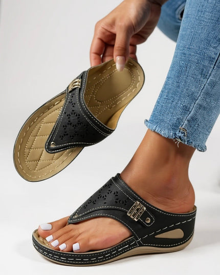 Black thong sandal with cushioned footbed and perforated strap detail, shown on foot