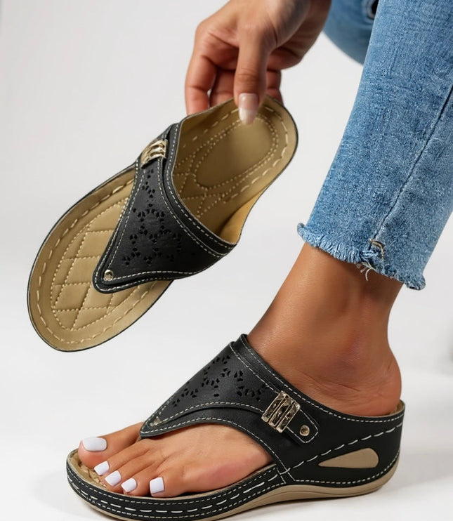 Black thong sandal with cushioned footbed and perforated strap detail, shown on foot
