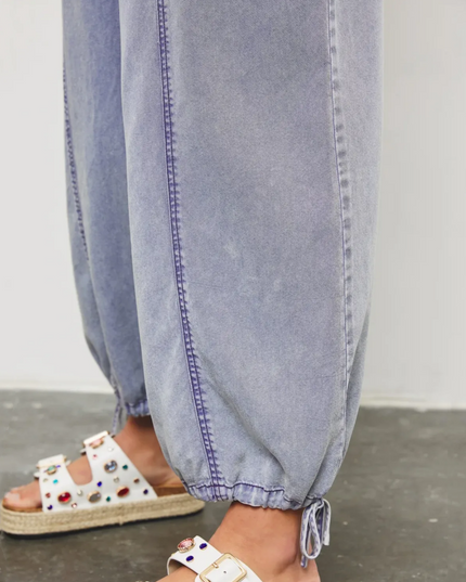 Close-up of light blue denim jumpsuit hem with drawstring detail and ankle cuff