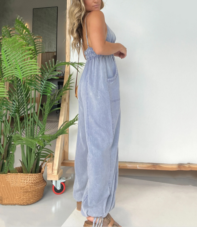 Back view of light blue denim jumpsuit showing open back design and wide-leg silhouette