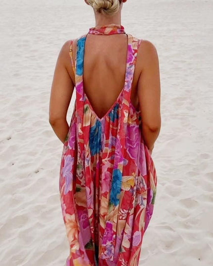 Rear view of a women's floral print V-neck maxi sundress, featuring a deep V-back and wide straps, on a sandy background.