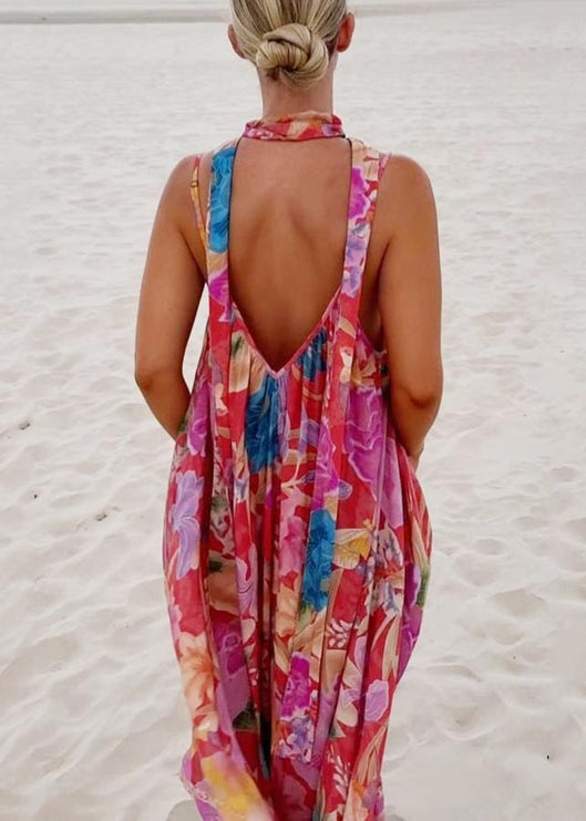 Rear view of a women's floral print V-neck maxi sundress, featuring a deep V-back and wide straps, on a sandy background.