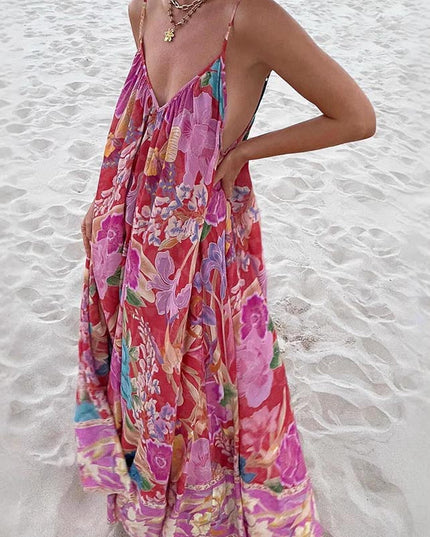 Front view of a women's floral print V-neck maxi sundress with vibrant pink, purple, and blue flowers, flowing on a sandy beach.