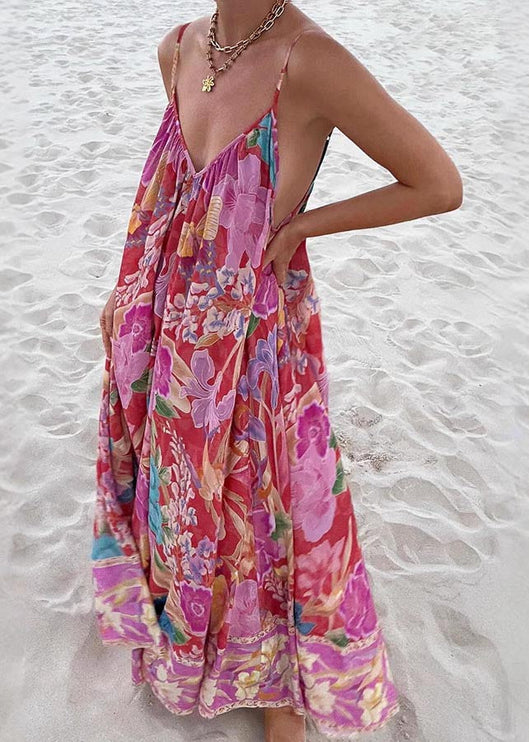Front view of a women's floral print V-neck maxi sundress with vibrant pink, purple, and blue flowers, flowing on a sandy beach.