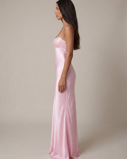 Side profile of pink beaded halter gown with long flowing silhouette