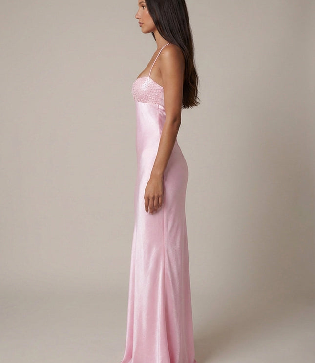 Side profile of pink beaded halter gown with long flowing silhouette