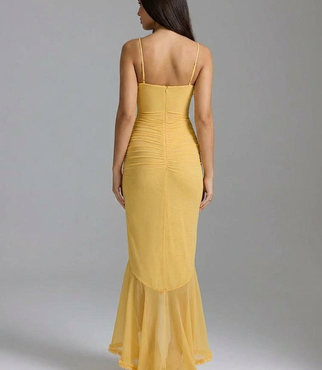 Back view of yellow maxi dress with fitted silhouette, sheer hem, and spaghetti straps