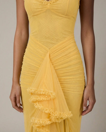 Close-up of yellow cocktail maxi dress showing ruched bodice, mesh fabric, and ruffle trim