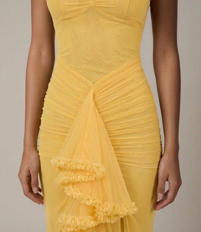 Close-up of yellow cocktail maxi dress showing ruched bodice, mesh fabric, and ruffle trim