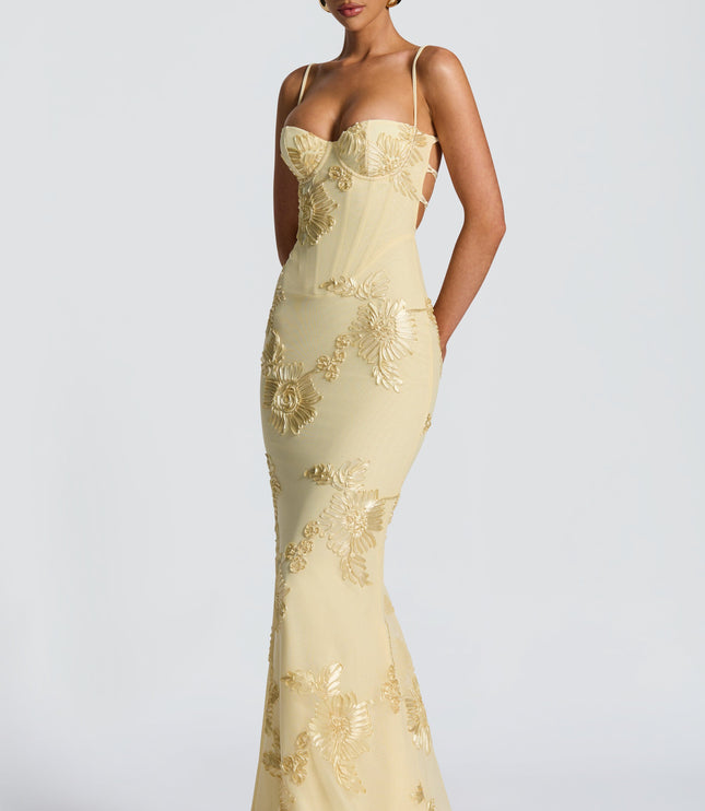 Side view of a women's formal floral embroidered maxi dress in light yellow, featuring a subtle side cutout and elegant floor-length design.