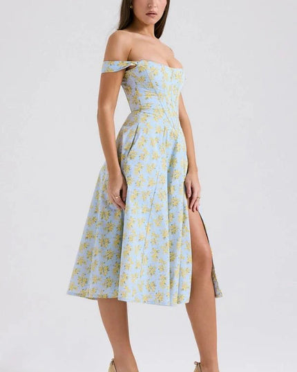 Side view of off shoulder midi dress with fitted waist, blue floral fabric, and front slit
