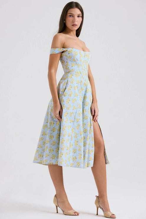 Side view of off shoulder midi dress with fitted waist, blue floral fabric, and front slit