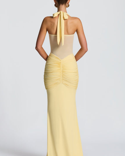 Back view of yellow halter maxi dress with tied halter straps and ruched skirt