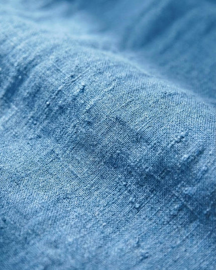 Close-up of light blue linen fabric texture showing weave detail