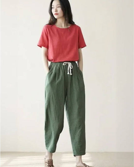 Sage green linen pants with cream tie waist in neutral room setting