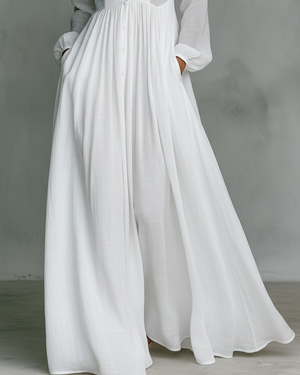 Close-up of white maxi dress skirt showing flowing pleated fabric and hem