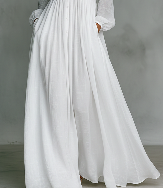 Close-up of white maxi dress skirt showing flowing pleated fabric and hem