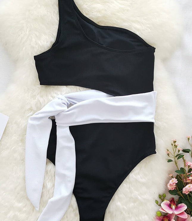 Black one shoulder one piece swimsuit with pink leopard print wrap tie on woven mat