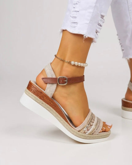 Close-up of tan beaded wedge sandal showing embroidered strap detail and buckle closure