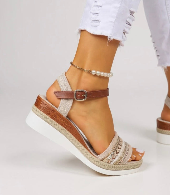 Close-up of tan beaded wedge sandal showing embroidered strap detail and buckle closure