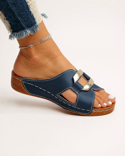 Navy platform slides with metallic double buckle straps and wooden tan sole, side view