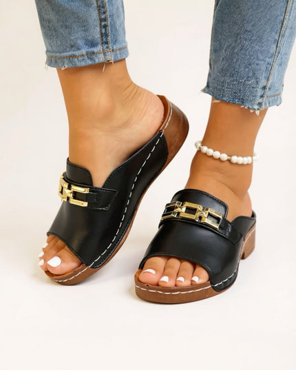 Black slide sandal with gold chain accent and cushioned sole from side view