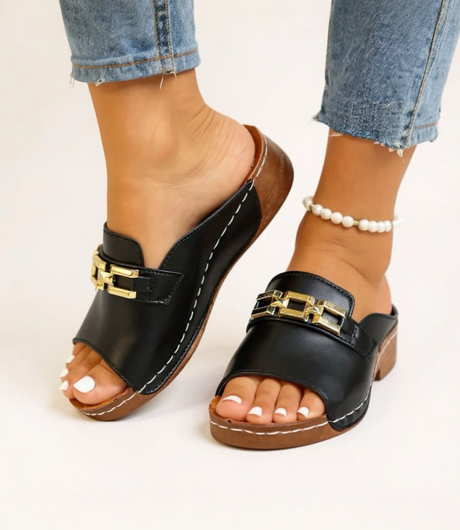 Black slide sandal with gold chain accent and cushioned sole from side view