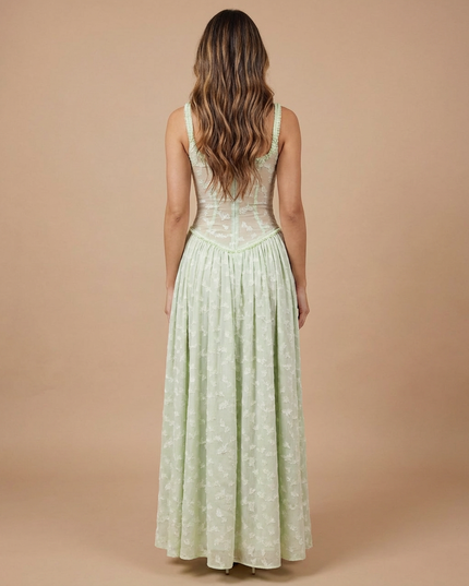 Back view of light green floral maxi dress with fitted sheer corset back and flowing skirt