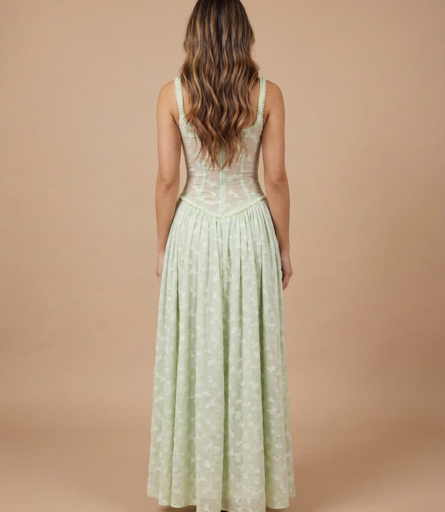 Back view of light green floral maxi dress with fitted sheer corset back and flowing skirt
