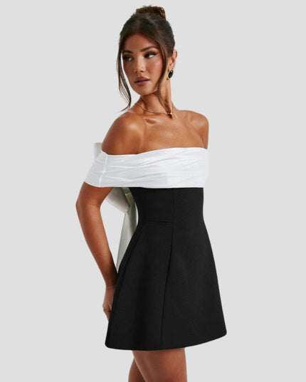 Side angle of black mini dress with draped white off-shoulder wrap and fitted waist