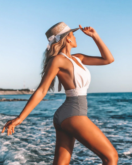 White halter one-piece swimsuit with ruched gray waist detail at beach