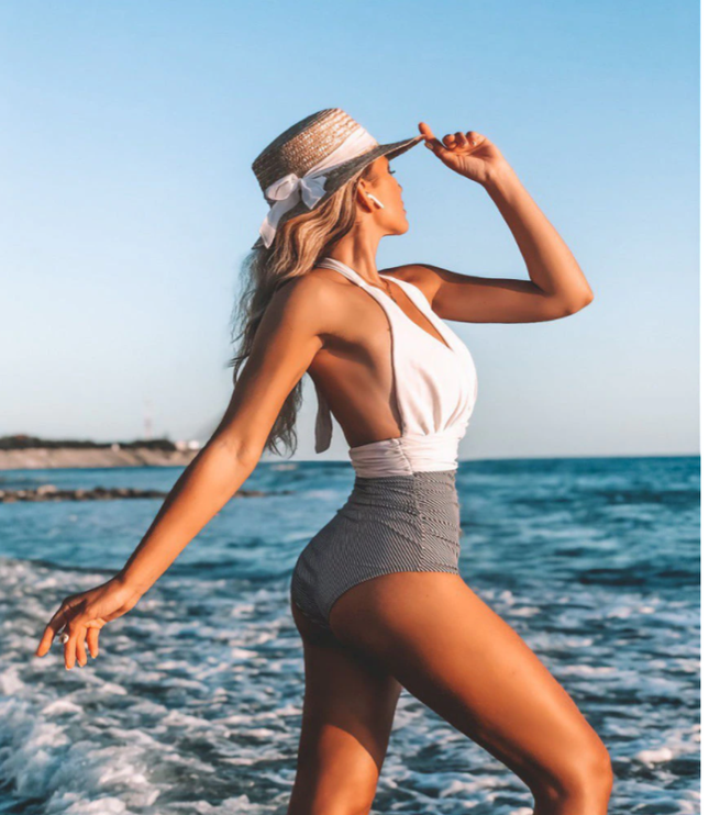 White halter one-piece swimsuit with ruched gray waist detail at beach