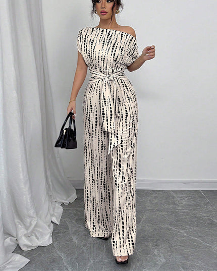 Front angled view of off-shoulder white jumpsuit with black dash pattern and flowing wide legs