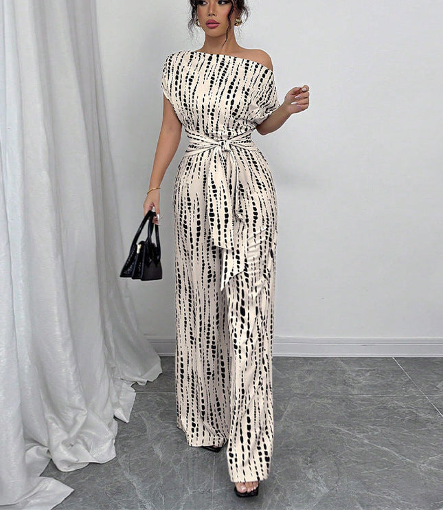 Front angled view of off-shoulder white jumpsuit with black dash pattern and flowing wide legs