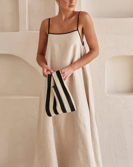 Cream spaghetti strap maxi dress styled with striped black and white clutch