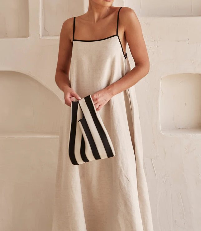 Cream spaghetti strap maxi dress styled with striped black and white clutch