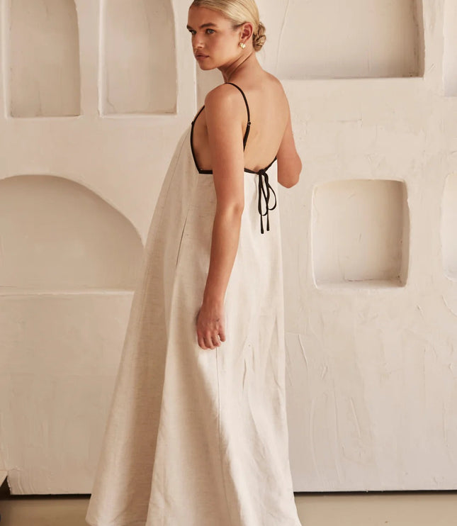 Back view of cream maxi dress showing open back with black tie straps