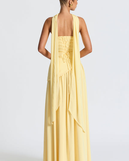 Back view of yellow strapless maxi dress with lace-up corset detail and layered asymmetrical skirt