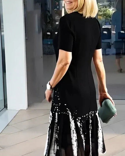 Back view of black midi dress with white abstract splatter hem and fitted short sleeves