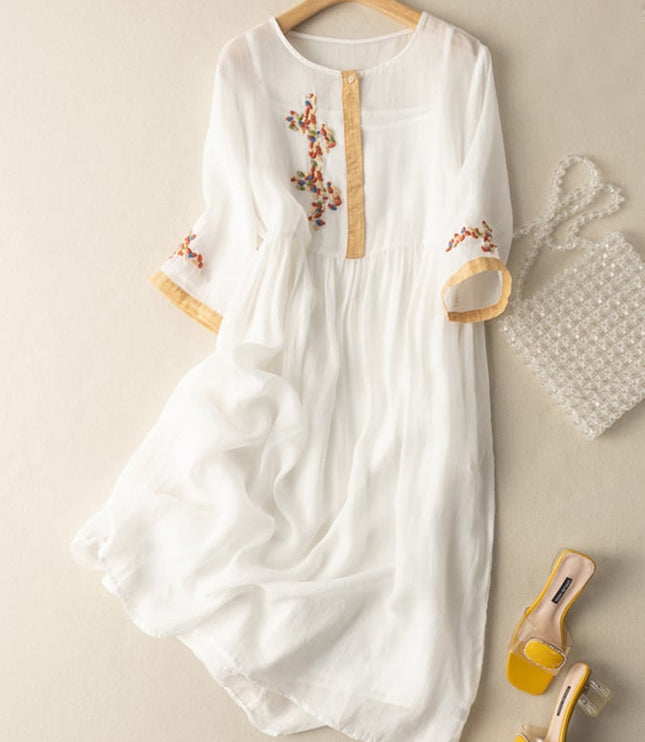 White women's summer embroidered midi dress with tan trim and sheer flowing skirt