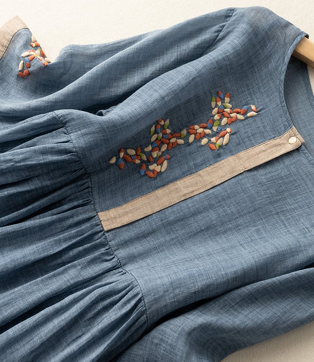 Close-up of blue embroidered midi dress with floral chest stitching and gathered waist
