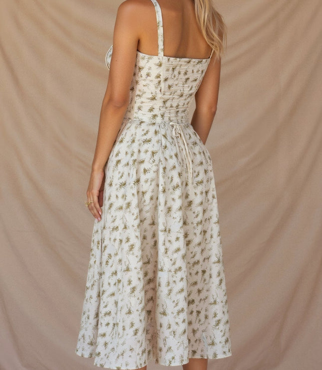 Back of cream floral midi dress with green leaf print, featuring a tie-back detail and elegant silhouette.