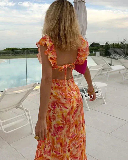 Back view of floral ruffle maxi dress with open back tie detail and flutter sleeves